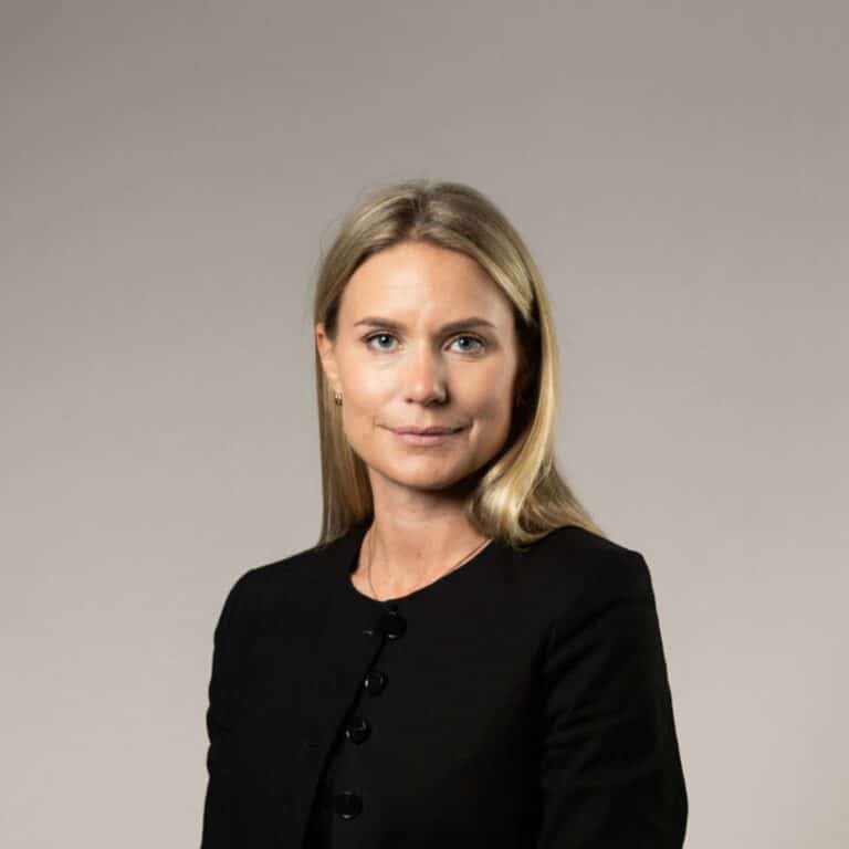 Blond kvinna som ler mot kameran i svart.