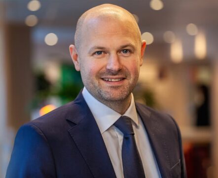 Man i kostym ler mot kameran