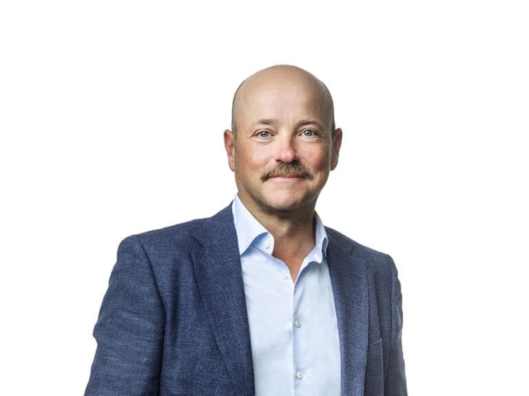 Man i kostym ler mot kameran