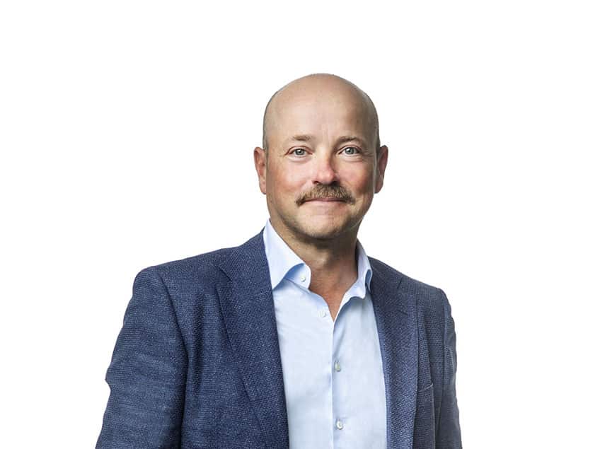 Man i kostym ler mot kameran