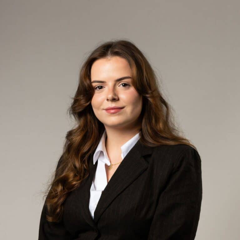 Leende mörkhårig kvinna med Vit skjorta och svart kavaj.