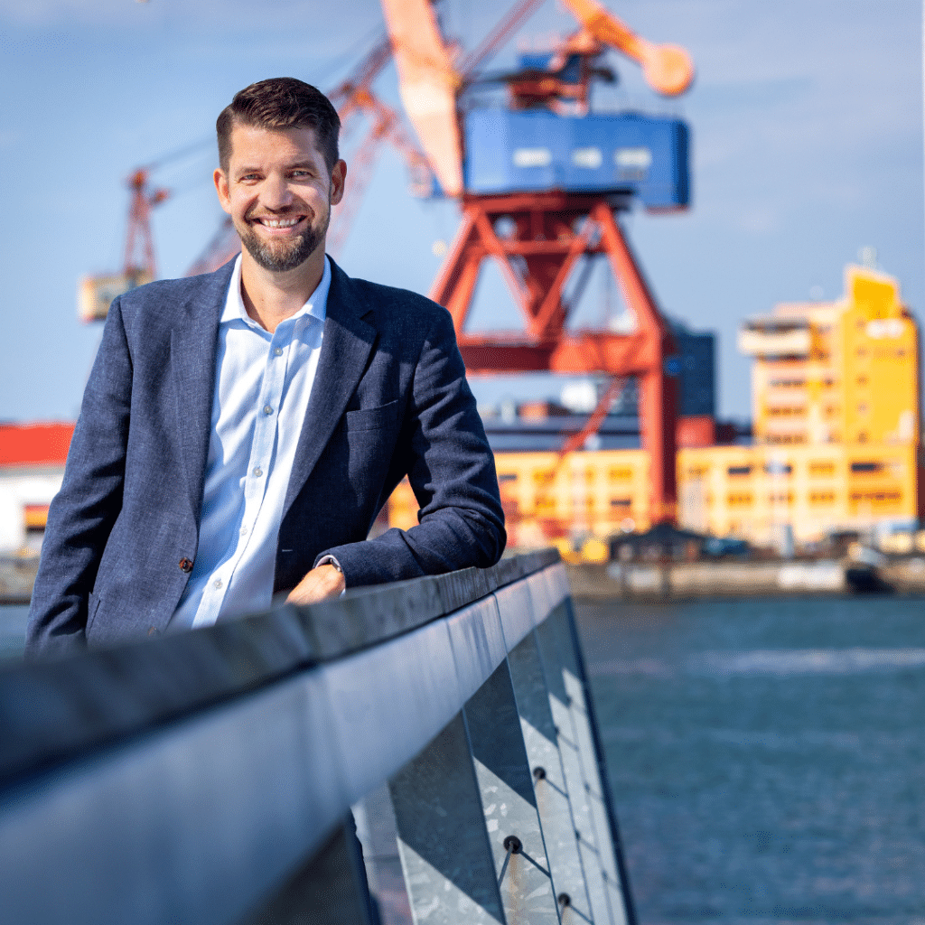 Man i blå kostym står med Göteborgs hamn i bakgrunden
