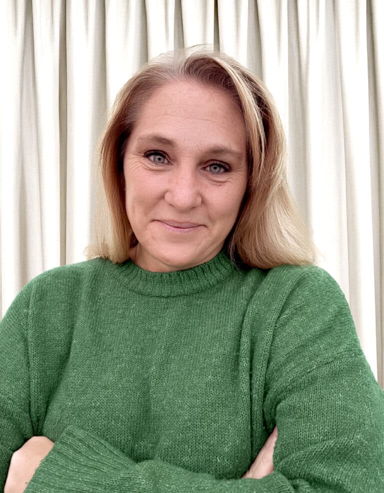 Kvinna i grön tröja ler mot kamera.