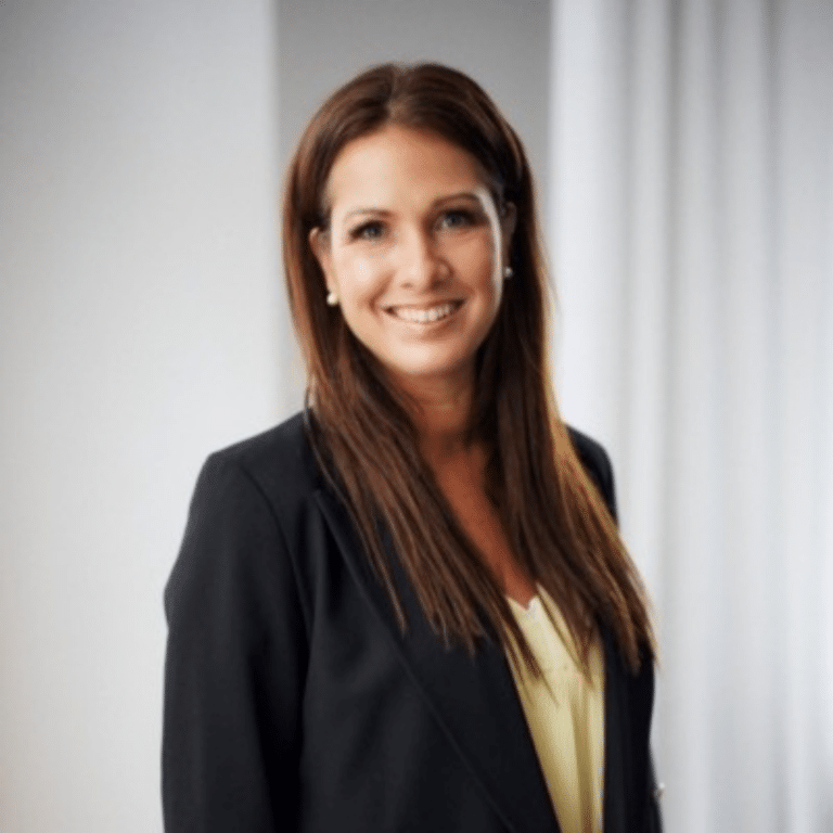 Kvinna med låmgt mörkt hår och kavaj ler in mot kameran