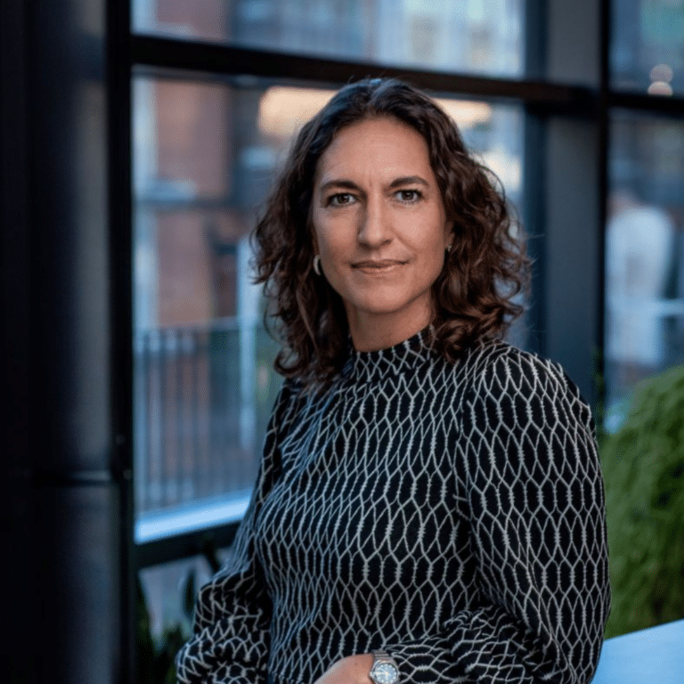 Kvinna i mönstrad klänning ler mot kameran