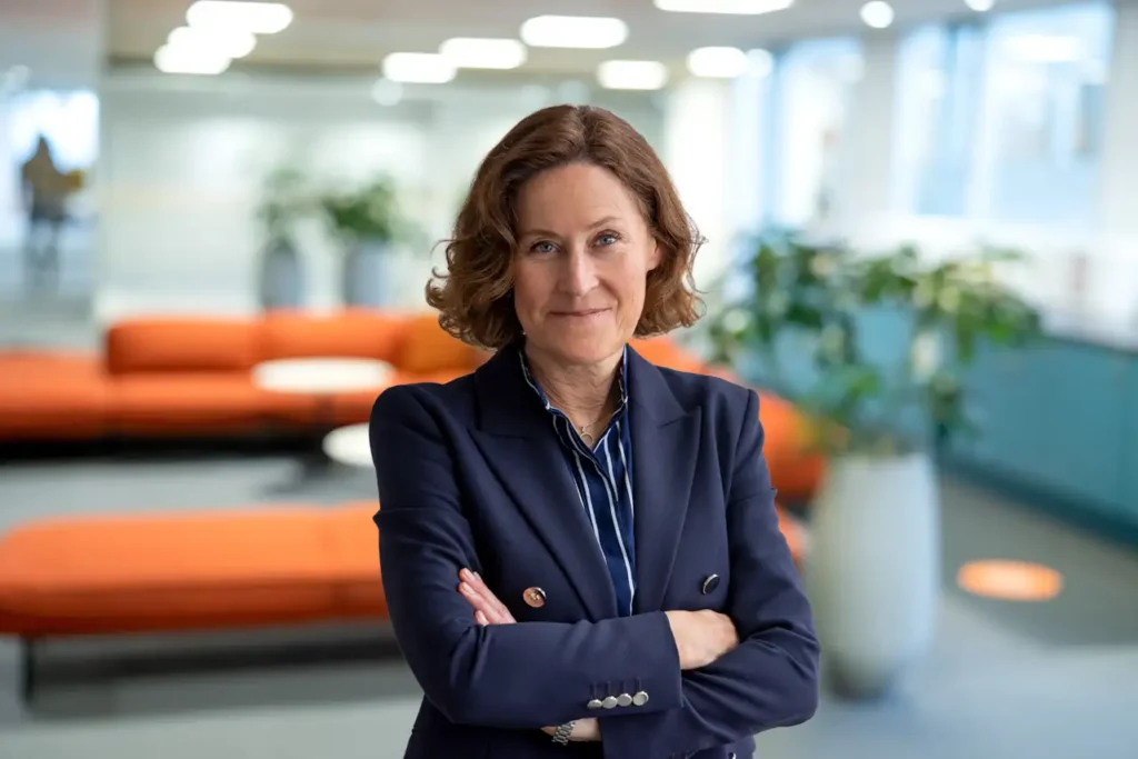 Kvinna i mörk kostym ler in i kameran.