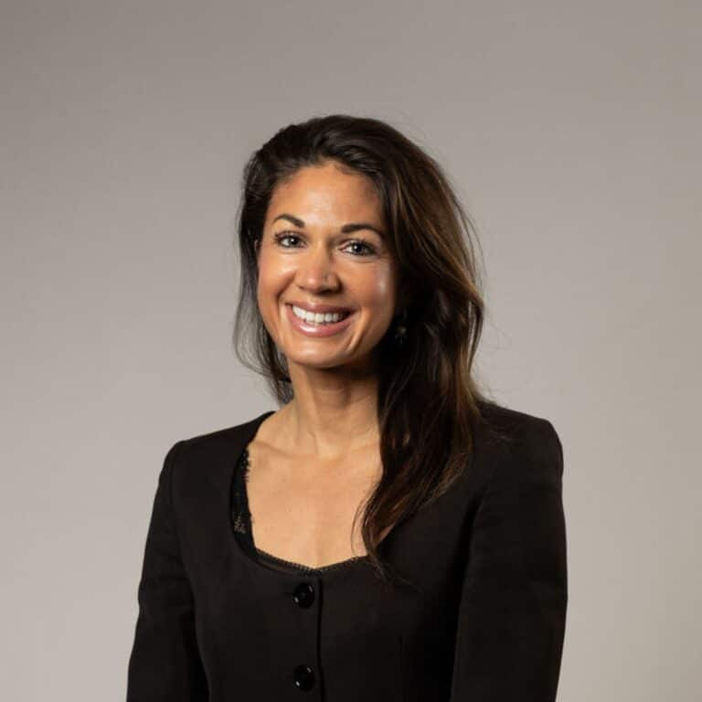 En kvinna med mörkt hår som ler mot kameran och har svart tröja på sig.