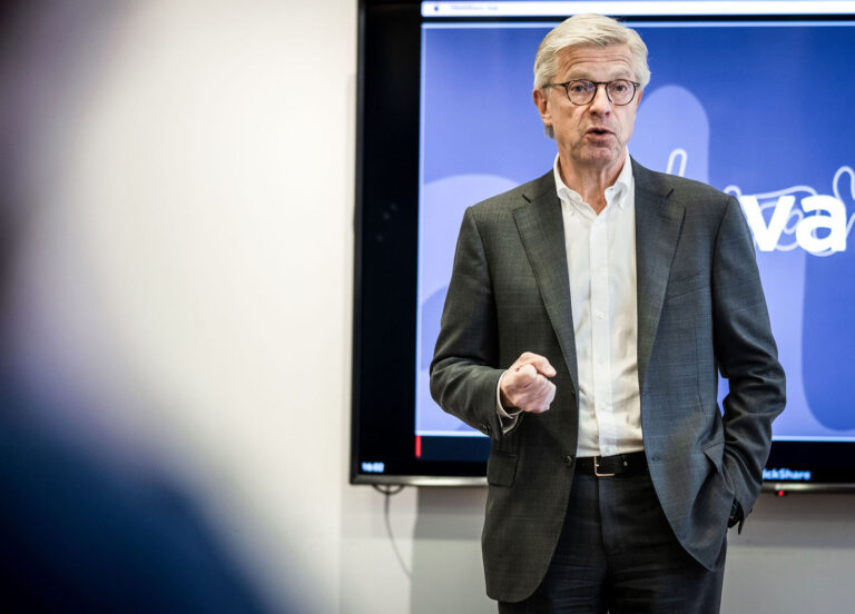 Man talar framför stor skärm med projektorbild.