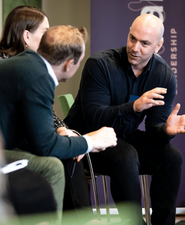 Tre personer diskuterar i ett ledarskapsprogram