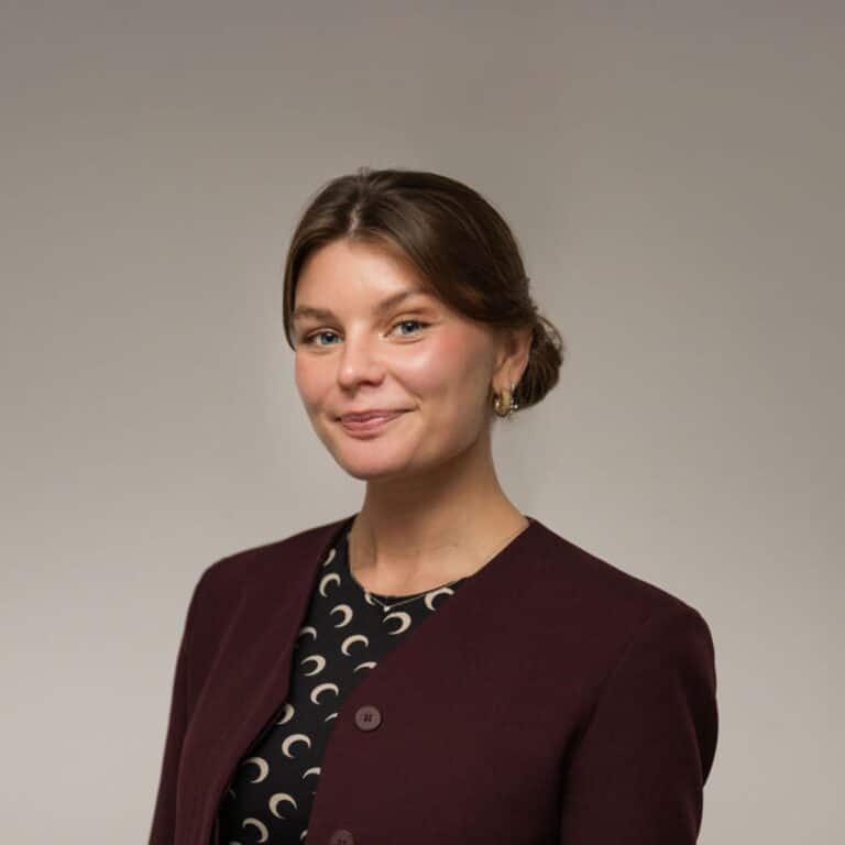 En Glad kvinna med håret i knut och vinröd kavaj.