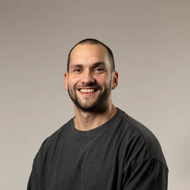 Glad kille med grå tröja som ler mot kameran