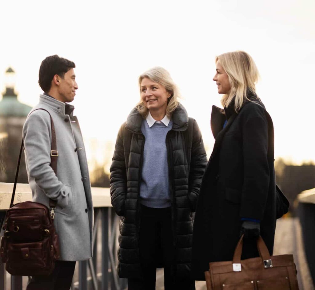 Tre personer samtalar utomhus i vinterkläder.