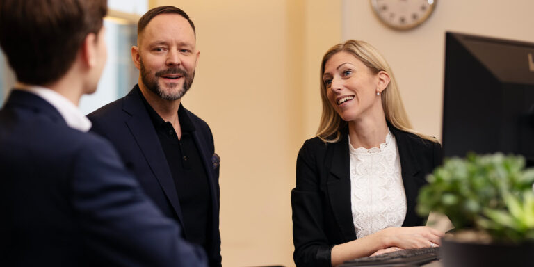 Två personer samtalar i kontorsmiljö, ser glad ut.