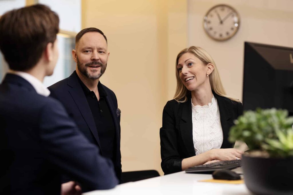 Tre personer som ler mot varandra på ett kontor.