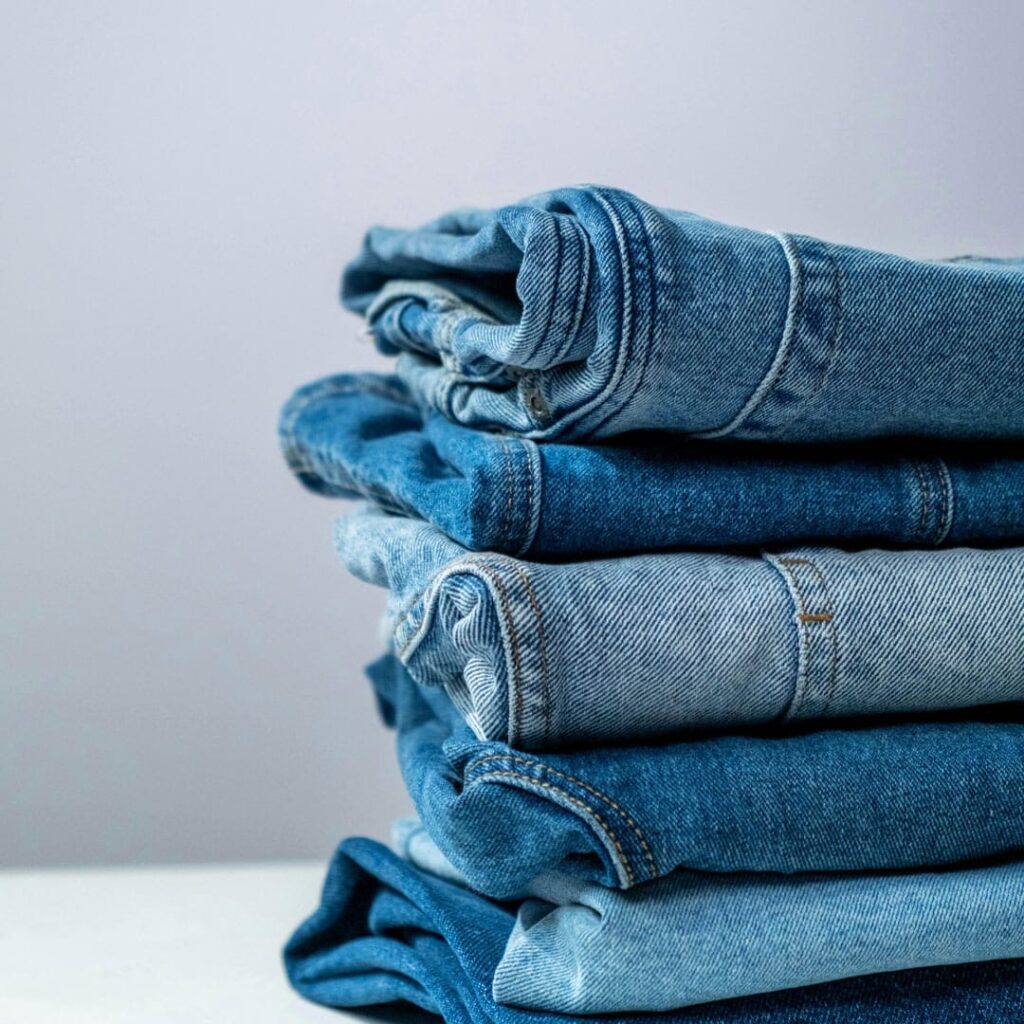 Jeans som ligger vikta i en hög på ett bord.