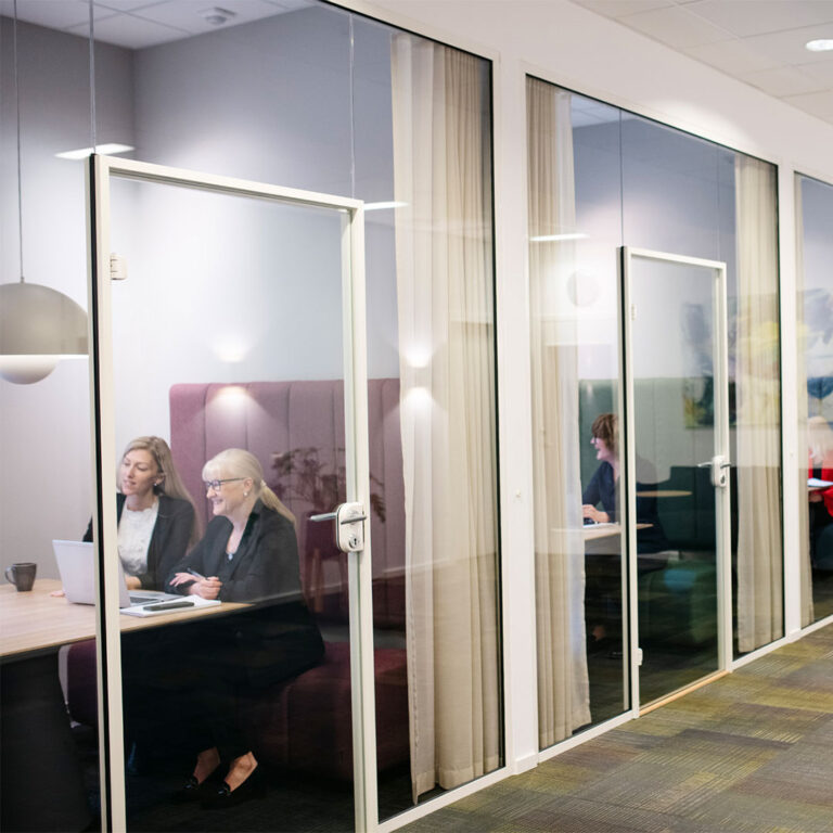 Personer sitter i små mötesrum i rad.