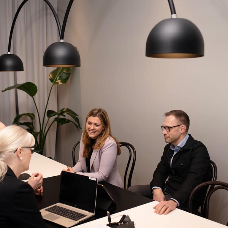 Två kvinnor och en man sitter i ett möte.