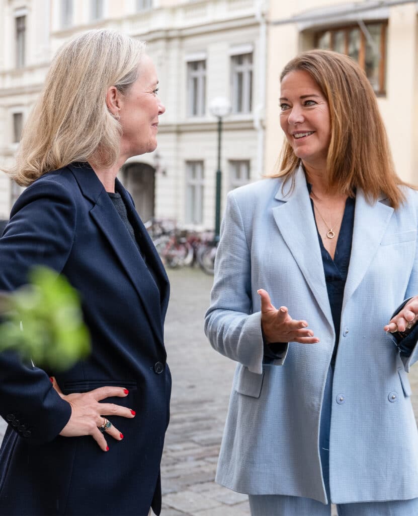 Två kvinnor står och pratar utomhus.