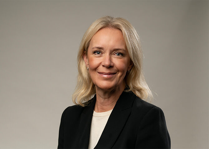 Kvinna ler framför neutral bakgrund.