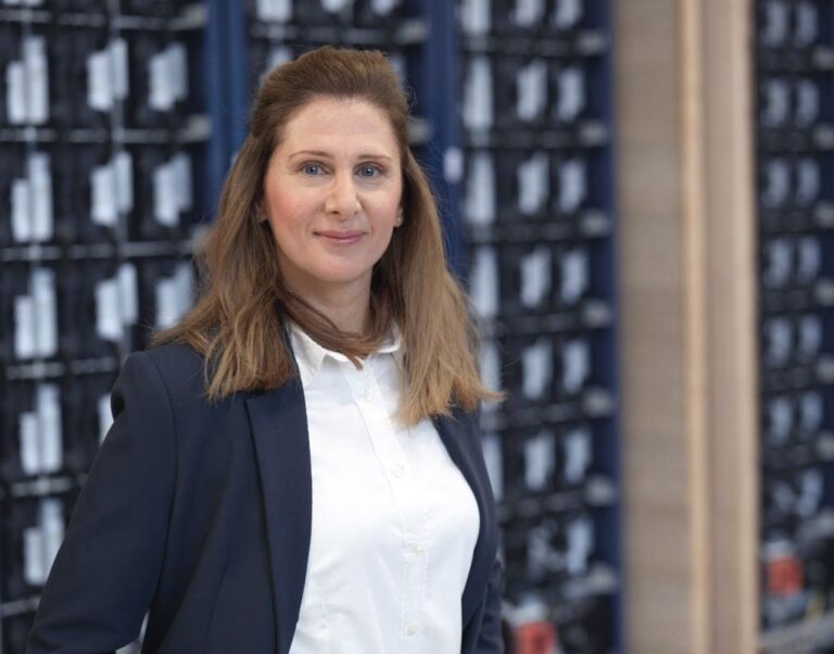 kvinna i vit skjorta och kavaj ler in mot kameran