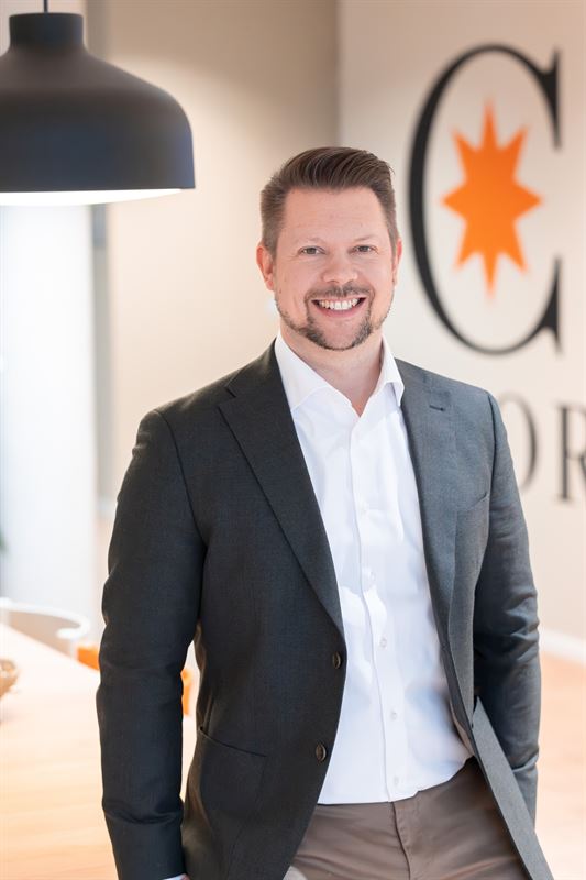 Man i kostym ler mot kameran