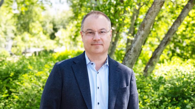 Man i mörk kostym ler mot kameran