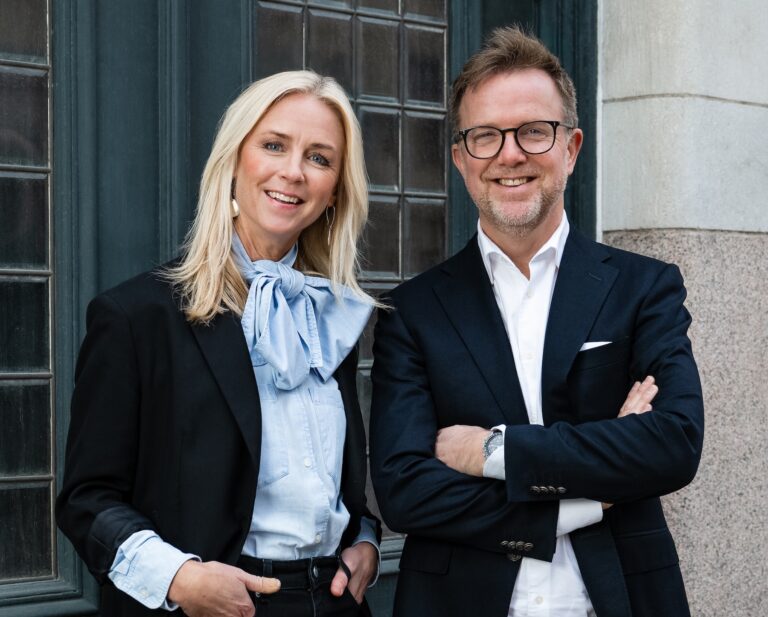 Porträtt framför en port med Petra Wigh & Lars Häggström på Novare